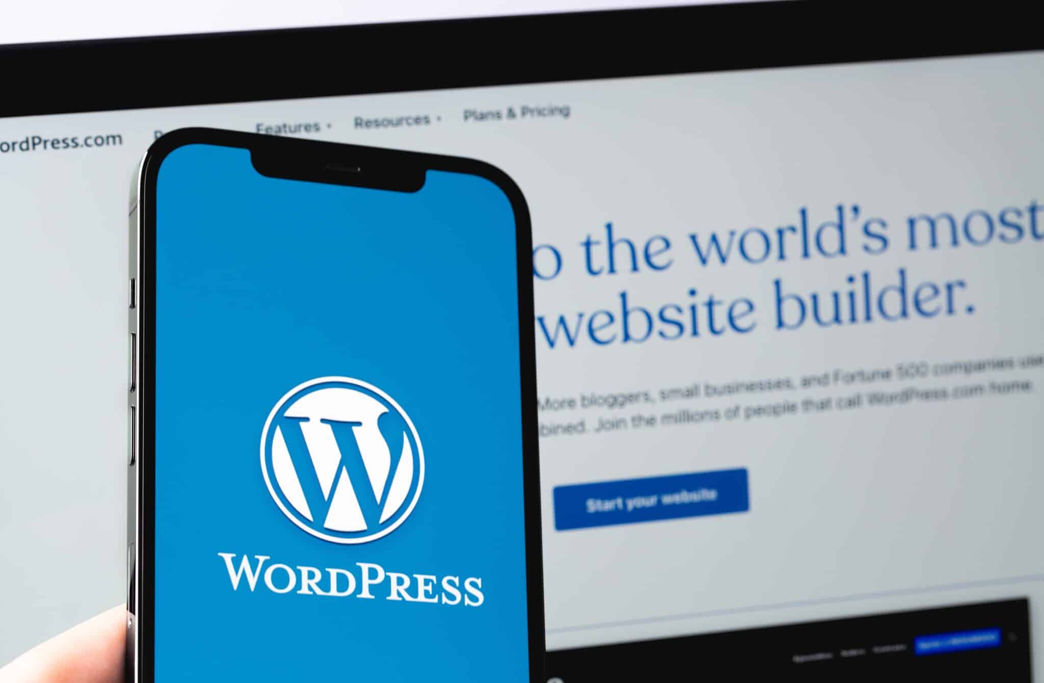 Wordpress logo on a phone with the WordPress website on a laptop in the background